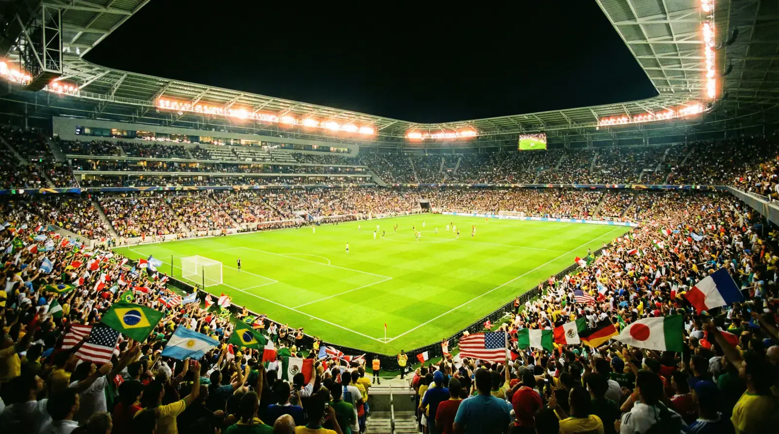 Estadio lleno durante un partido nocturno del Mundial 2026 con las banderas de las selecciones participantes